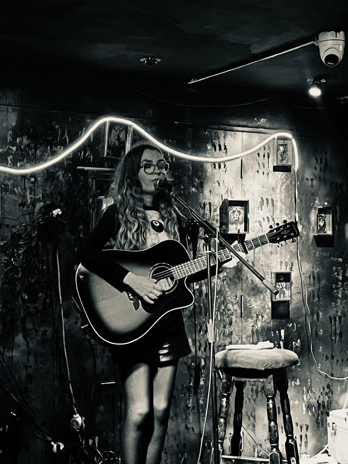Black and white shot of Aimée beneath a neon wave