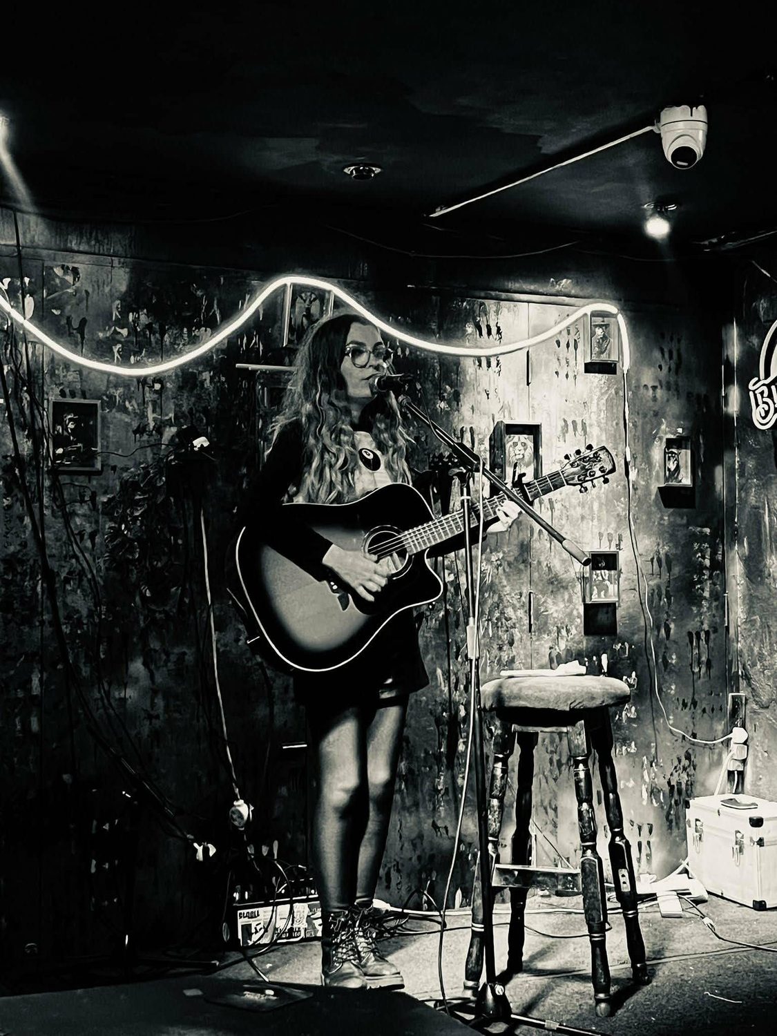 Black and white performance shot under string-light neon