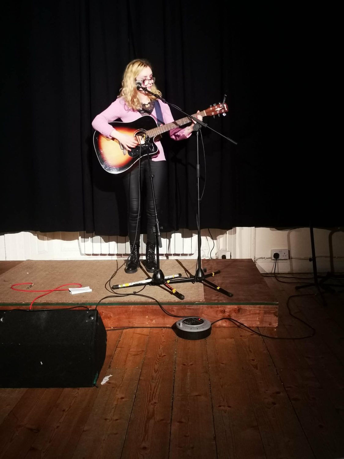 Aimée on a small stage in a pink cardigan